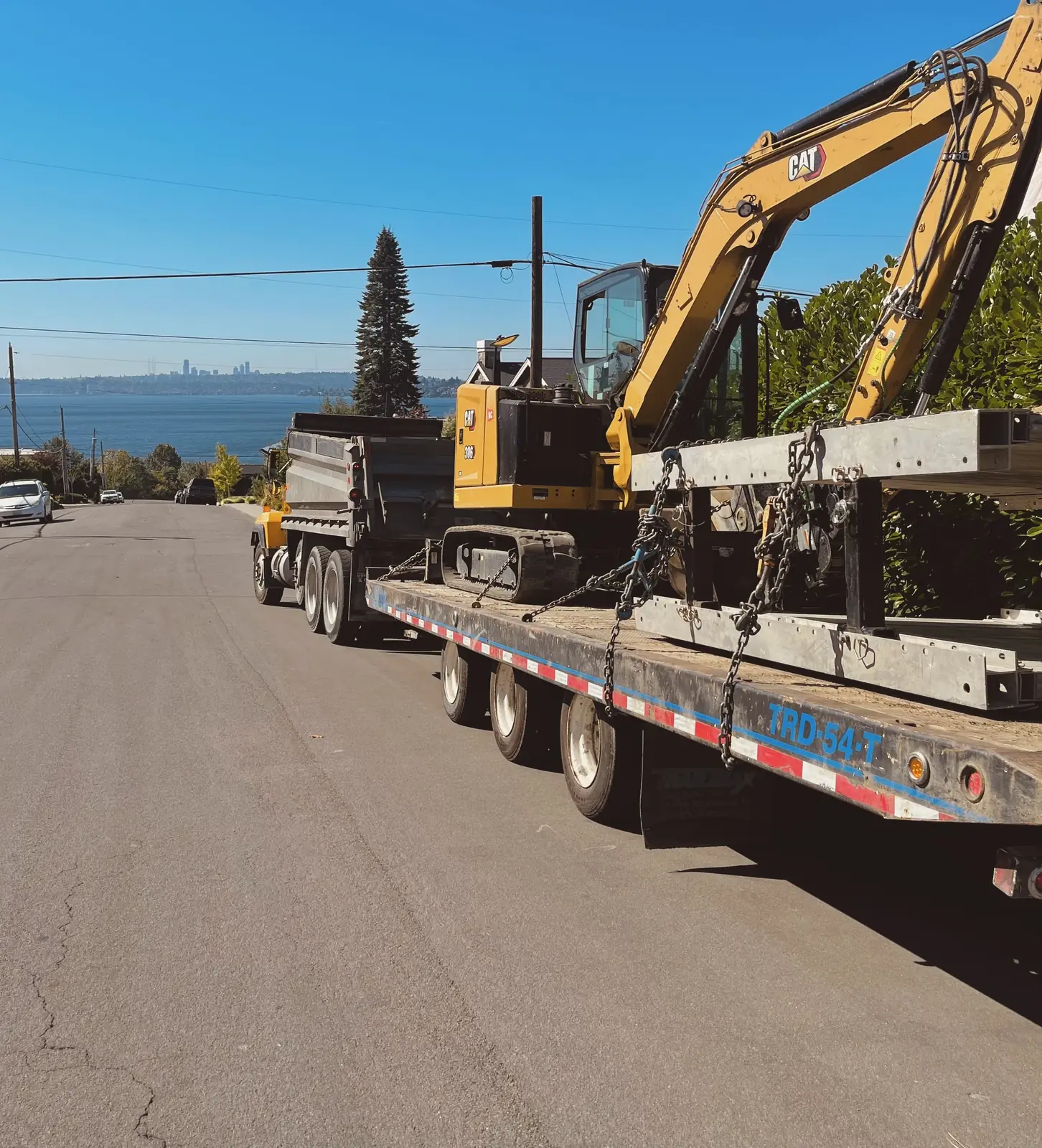 Always Active hauling a CAT excavator with the Seattle skyline behind